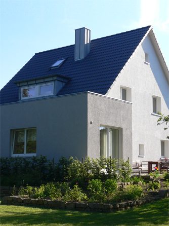 Saniertes Einfamilienhaus mit weißem Putz und dunklem Dach