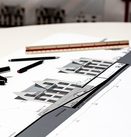 Architekturmodell und Pläne mit Maßstab auf dem Zeichentisch