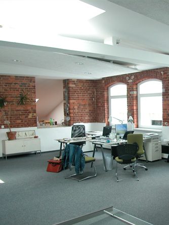 Büro mit Backsteinwänden und Rundbogenfenstern in einem Industriegebäude